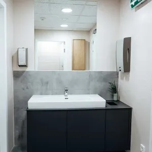 Moderner Waschraum mit großem Spiegel, grauen Fliesen und dunklem Unterschrank