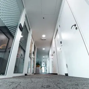 Flur mit weißen Türen, Glastrennwänden und grauem Teppichboden