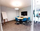 Kleiner Meetingraum mit blauem Stuhl-Set und Bildschirmwand