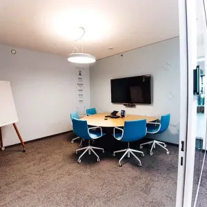 Kleiner Meetingraum mit blauem Stuhl-Set und Bildschirmwand