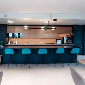 Kaffeebar mit Holzfront, blauen Barhockern und M&M’s Snackautomat