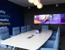 Konferenzraum mit blauen Sesseln, Werten an der Wand und Doppelbildschirm