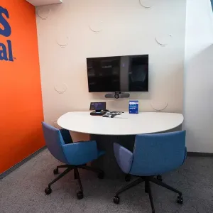 Kleiner Besprechungsraum mit oranger Ben’s Original Wand und Bildschirm