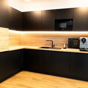 Moderne Teeküche in Schwarz und Holz mit Kaffeemaschine und Beleuchtung