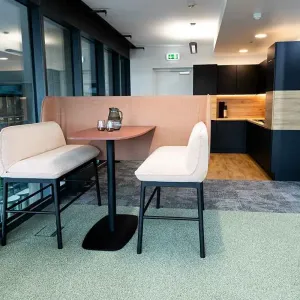 	Café-Bereich mit Sitzbank, Tisch und Blick zur modernen Büroküche