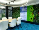 Besprechungsraum mit grüner Pflanzenwand und großem Holztisch