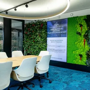 Besprechungsraum mit grüner Pflanzenwand und großem Holztisch