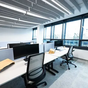 Ergonomische Arbeitsplätze mit Monitoren und großen Fenstern im Open Space