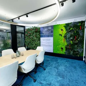 Besprechungsraum mit grüner Pflanzenwand und modernem Holztisch